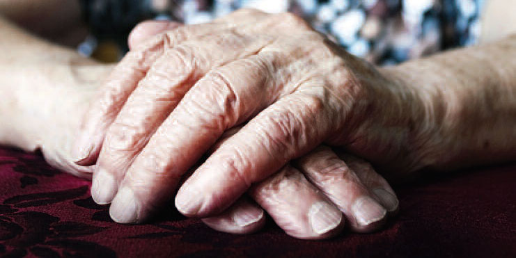 hands of older woman resting on table
