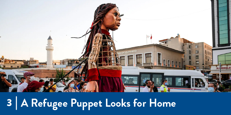 3 - A Refugee Puppet Looks for Home The puppet being moved by a group of people
