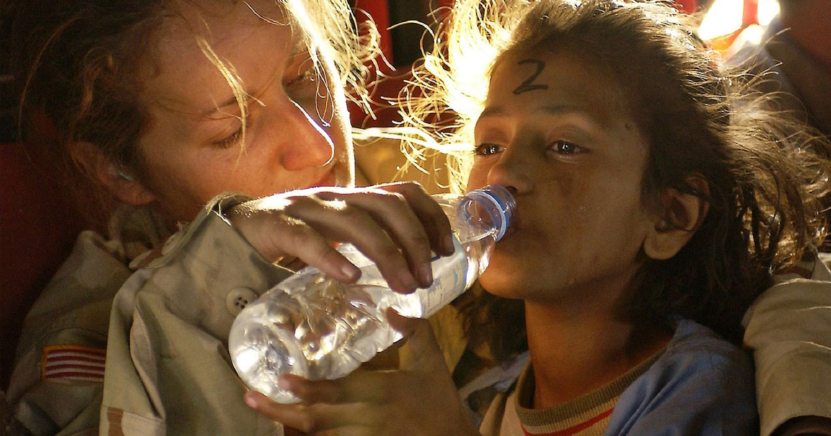 humanitarian worker giving water to child