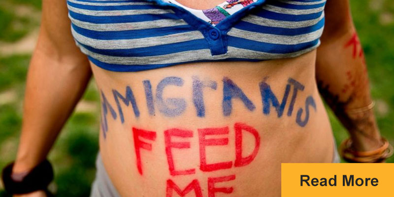 pregnant women with immigrants feed me written on stomacj