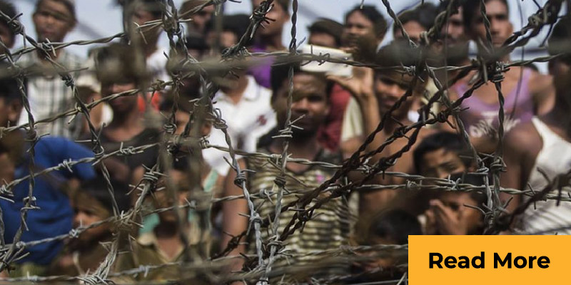 migrants behind barbed fence