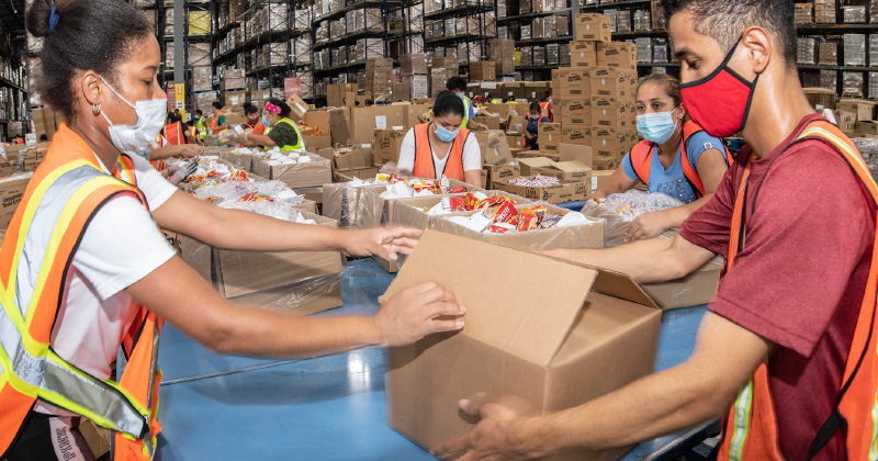 Warehouse workers wearing masks move boxes 