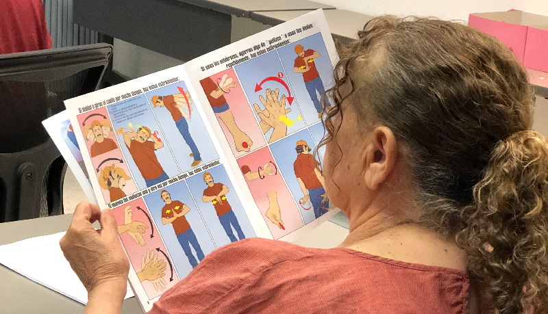 A woman reads a guide to health and safety in Spanish