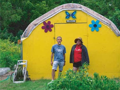 Two people stand in front of a shed