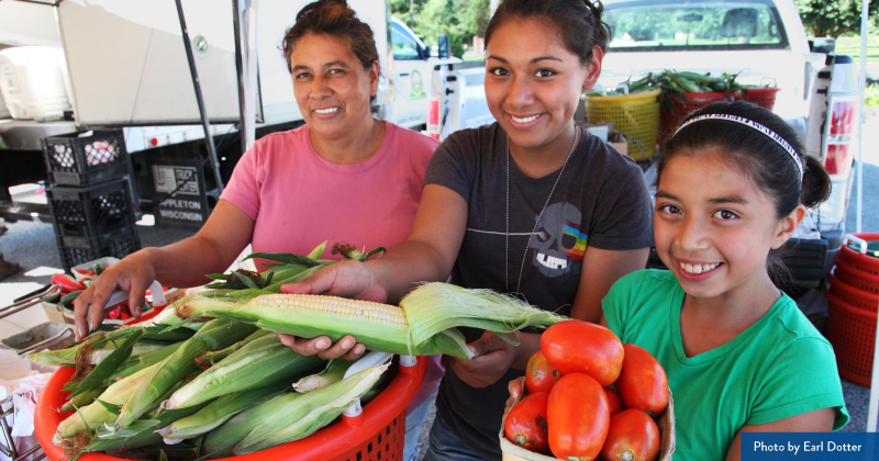A family sells produce at a farmers market