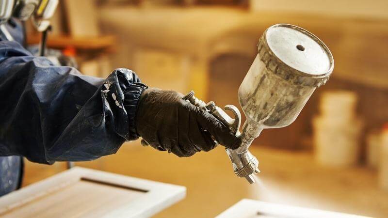 A worker sprays paint while wearing protective equipment