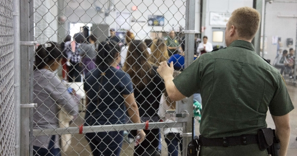 CBP officer lets detainees out of holding area.
