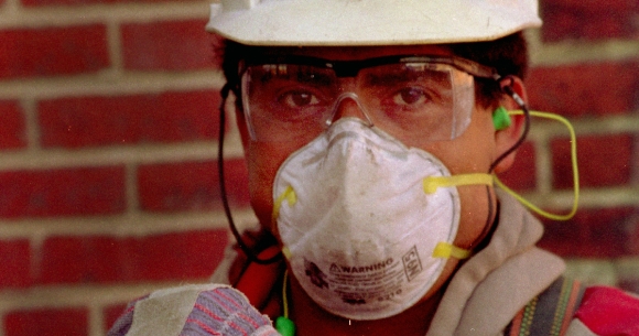 A construction worker wearing a mask and protective equipment