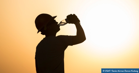 A person wearing protective helmet drinks water