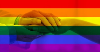 physician holding patients hand with pride flag behind