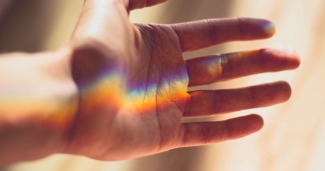 hand outstretched with rainbow light