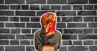 woman in hijab from behind facing brick wall