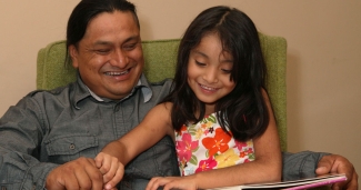 child reading a book with her dad
