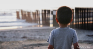 Child looks at border fence