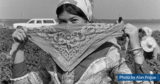 A farmworker ties a bandana around her face