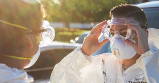 A clinician putting on PPE