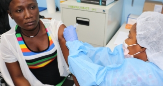 A woman is vaccinated by a clinician in PPE