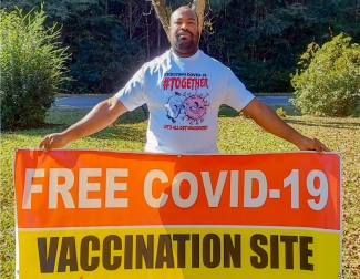 A volunteer holding a sign for vaccination
